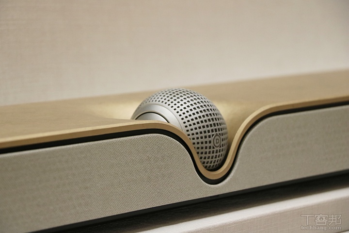 Devialet Dione Soundbar 造型採用俐落的長方體機身，內建多顆單體設計，無需搭配額外低音喇叭就能輸出深沈的極低頻，機體中間更鑲嵌一顆可旋轉的球型結構，不只視覺上形成強烈的「圓與方」對比，這顆球體實則是能調整高音指向的單體，依照擺放方式（平放或壁掛）自動對應最佳發聲角度。