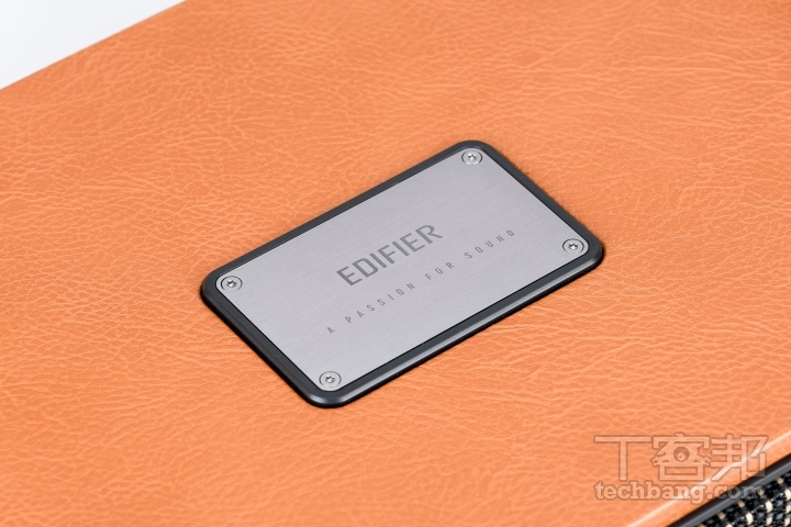 品牌金屬標四邊以仿皮革質感的荔枝皮革紋包覆，搭配頂部鑲嵌品牌金屬銘牌質感。