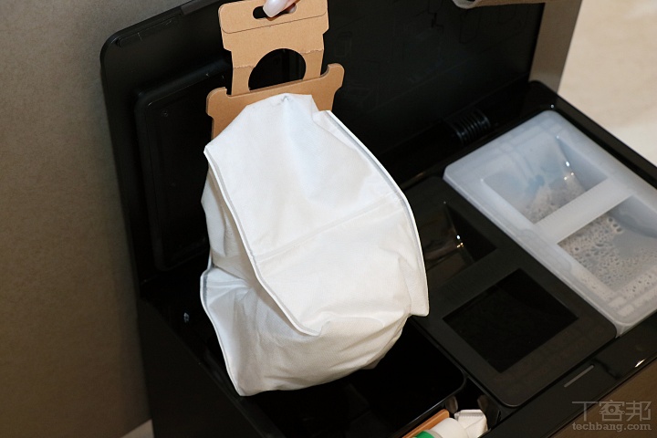 基座左側為密封式集塵袋，每次機器人回到底座後都會自動啟動集塵程序，將主機集塵盒內的灰塵集中至集塵袋中；官方表示單一集塵袋最長可使用約 75 天，實際更換頻率則視居家環境與清掃次數而定。